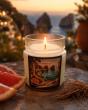 Bougie parfumée Candles Adventure devant un paysage côtier au coucher du soleil
