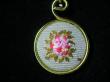 Détail médaillon en broderie parme, jaune et rose soutenu sur tissu vert, cordon organdi et coton ciré parme. Diamètre 30mm. longueur 42cm;