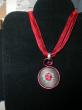 médaillon en broderie rouge sur tissu grisé, cordon organdi et coton ciré rouge. Diamètre 30mm. longueur 42cm;