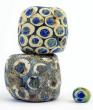 Pascal Guegan
L’exposition ouvre avec un petit rappel historique. En effet, le matériau verre est connu depuis fort longtemps, travaillé comme « glaçure » par exemple sur les céramiques (fine pellicule de verre) dès le VIème millénaire AEC*. 
Pourtant, c’est en Syrie, vers le milieu du IIème millénaire AEC* que l’artisanat du verre à proprement parler voit le jour. Les premiers verriers façonnent des objets par dépôts successifs de couches de pâte de verre en fusion autour d’un noyau de sable et d’argile de la forme souhaitée ; noyau ensuite détruit pour laisser apparaître plat, flacons et autres contenants. 
Viendront s’ajouter à ces savoir-faire, dans le millénaire suivant, la technique du verre mosaïqué et l’art du soufflage... 

Les premières perles en verre elles semblent avoir été fabriquées vers le milieu du IIIème millénaire AEC*, en Mésopotamie (Sumer), sans doute pour imiter les pierres gemmes (turquoise, lapis lazuli...). 
Le Nouvel Empire égyptien (vers - 1350) est la première grande époque de travail du verre, les techniques étant de plus en plus élaborées, le verre supplantant alors les gemmes. 
Les perles commencent à se diffuser dans le monde grec, et à partir de -800, les Phéniciens et Carthage jouent un rôle fondamental tant au niveau de la créativité que de la diffusion dans tout le bassin méditerranéen. 


Pour présenter cette histoire, la mise à disposition de pièces anciennes issues de la collection particulière de Pascal Guegan « L’Age du Verre » permet de découvrir des perles et autres petits objets issus des fouilles de Carthage, d’Egypte ou encore émanant de la Rome Antique... 

